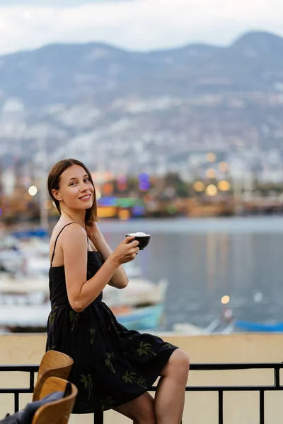 Mujer disfrutando de una taza de café cerca del mar —  Fotos de Stock