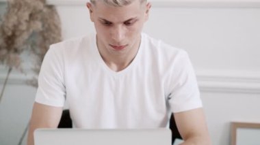 Genç adam dizüstü bilgisayar kullanıyor. Beyaz oda.