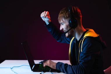 Kişisel bilgisayarında video oyunları oynayan kulaklıklı bir oyuncu.