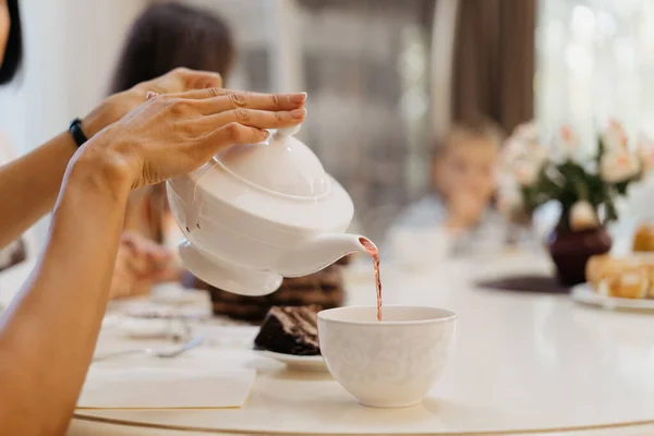 Kobieta leje herbatę z białego czajnika w domu — Zdjęcie stockowe