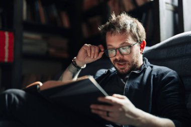 Yetişkin öğrenci üniversite kütüphanesinde kitap okuyor.