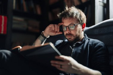 Yetişkin öğrenci üniversite kütüphanesinde kitap okuyor.