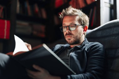 Yetişkin öğrenci üniversite kütüphanesinde kitap okuyor.