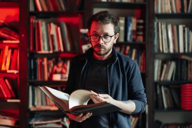 Yetişkin öğrenci üniversite kütüphanesinde kitap okuyor.