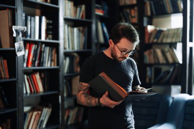 Yetişkin öğrenci üniversite kütüphanesinde kitap okuyor.
