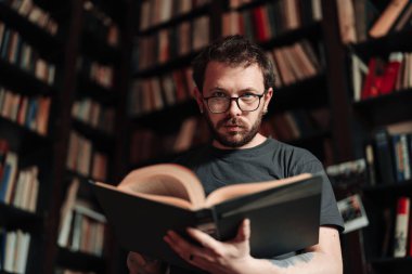 Yetişkin öğrenci üniversite kütüphanesinde kitap okuyor.