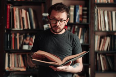 Yetişkin öğrenci üniversite kütüphanesinde kitap okuyor.