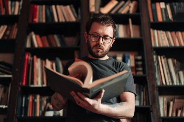 Yetişkin öğrenci üniversite kütüphanesinde kitap okuyor.