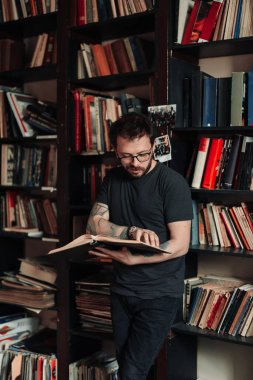 Yetişkin öğrenci üniversite kütüphanesinde kitap okuyor.