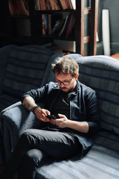 Hombre sentado en un sofá usando un smartphone — Foto de Stock