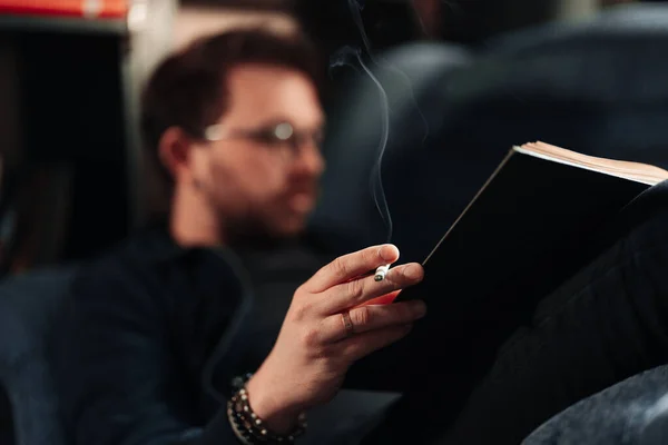 Chiudi mano uomo che tiene una sigaretta durante la lettura — Foto Stock