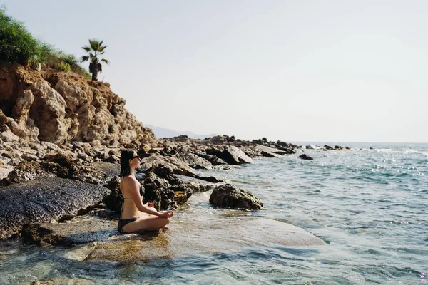 Traveler donna gode la sua vacanza sulla costa del mare praticando yoga — Foto Stock