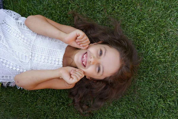 Gadis kecil yang cantik berbaring di atas potrait rumput — Stok Foto