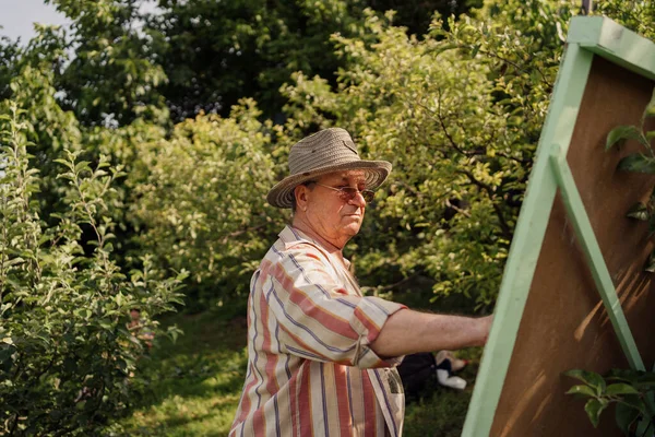 Ανώτερος άνθρωπος ζωγραφική στον κήπο του — Φωτογραφία Αρχείου