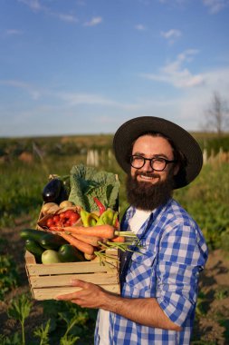 Çiftçi bir kutu sebze tutuyor. Sonbahar hasadı.
