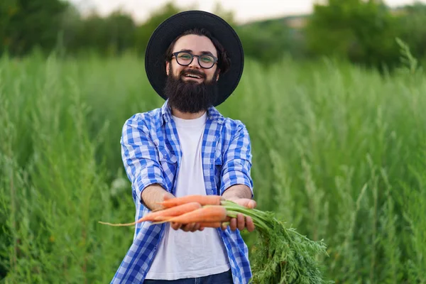 Усміхнений чоловік тримає в руках купу моркви — стокове фото