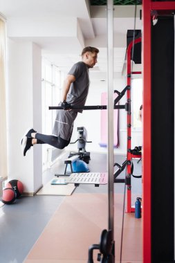 Genç çekici adam spor salonundaki parmaklıkları kaldırıyor.