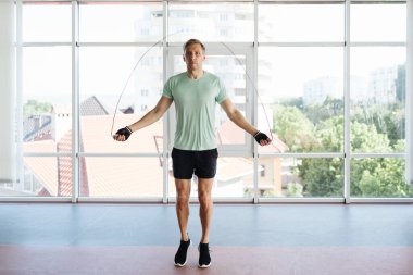 Yakışıklı genç adam atlıyor ip atlıyor idman yapıyor.