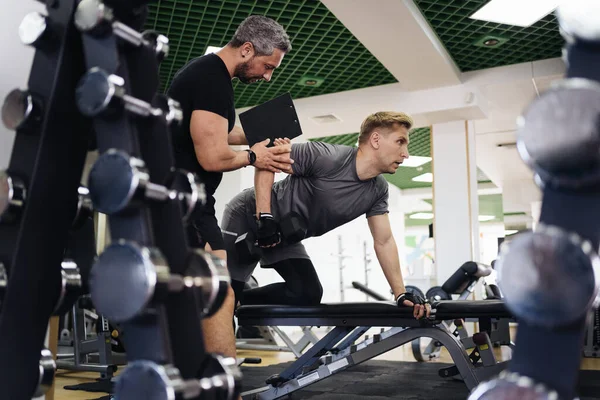 Jovem tem treino com personal trainer no ginásio — Fotografia de Stock