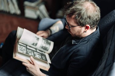 Yetişkin öğrenci üniversite kütüphanesinde kitap okuyor.