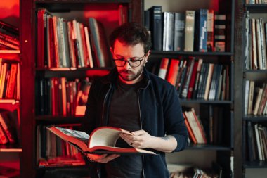 Yetişkin öğrenci üniversite kütüphanesinde kitap okuyor.