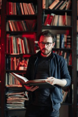 Yetişkin öğrenci üniversite kütüphanesinde kitap okuyor.