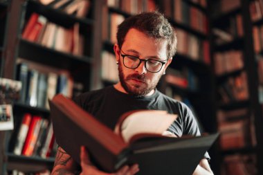 Yetişkin öğrenci üniversite kütüphanesinde kitap okuyor.