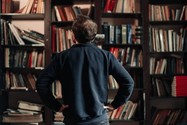 Erwachsener Student schaut in der Universitätsbibliothek nach einem Buch — Stockfoto