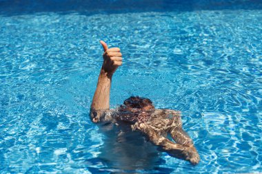 Havuzda el işaretleri gösteren bir adam.