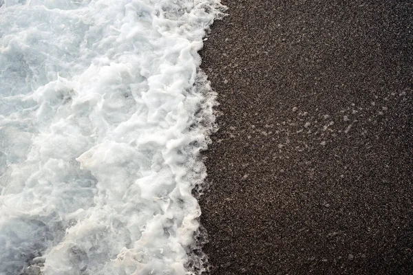 Suave ola espumosa blanca en una playa de arena. —  Fotos de Stock