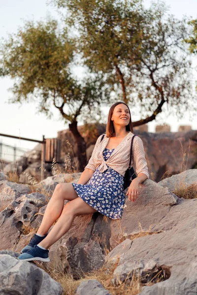 Mujer sonriente viajera descansando en una roca al aire libre —  Fotos de Stock
