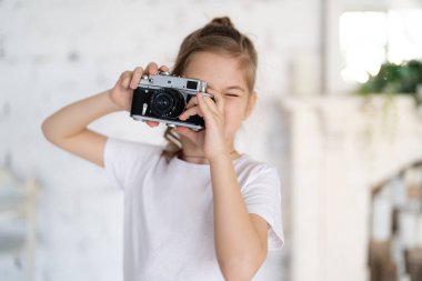 Güzel beyaz çocuk evinde, evinde, film kamerasından fotoğraf çektiriyor. Vintage filtre tonu.