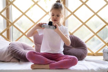 Güzel beyaz çocuk evinde, evinde, film kamerasından fotoğraf çektiriyor. Vintage filtre tonu.