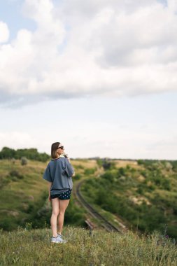 Carefree young woman daydreaming in nature with beautiful clouds in background