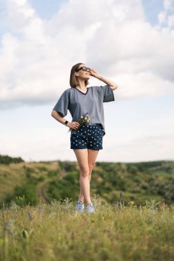 Carefree young woman daydreaming in nature with beautiful clouds in background