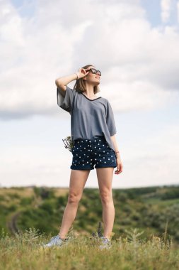 Carefree young woman daydreaming in nature with beautiful clouds in background