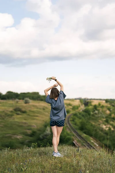 Carefree young woman daydreaming in nature with beautiful clouds in background