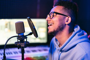 Erkek vokalist, şarkıcı, kıvırcık saçlı podcaster, ses stüdyosundaki kulaklıklar yeni bir melodi veya albüm kaydediyor..