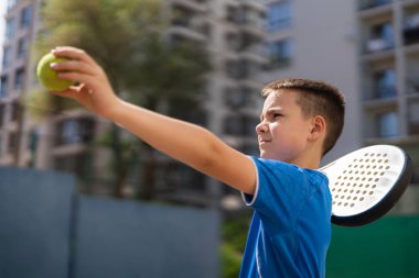 Açık alanda raketle padel oynayan genç bir delikanlı.
