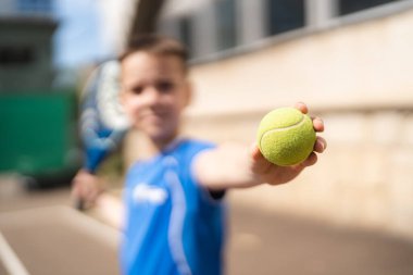 Açık alanda raketle padel oynayan genç bir delikanlı.
