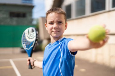 Açık alanda raketle padel oynayan genç bir delikanlı.