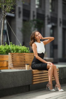 Çekici bir kadın yazın bankta oturuyor. 