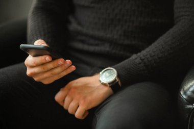 Cep telefonu siyahlı bir adamın elinde. 