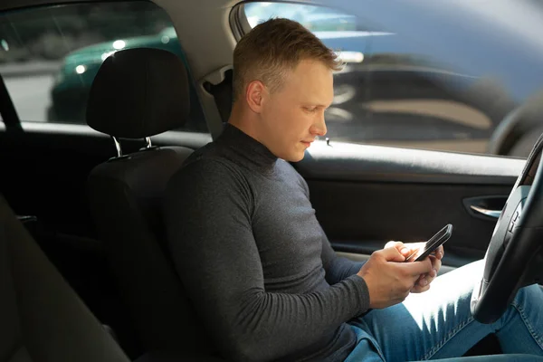 young businessman driving a car with a phone