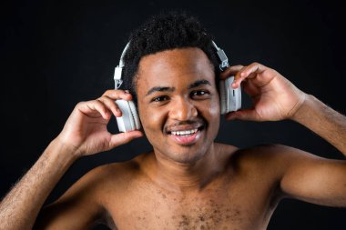 Siyah arka planda kulaklıklı neşeli Afrikalı adam.