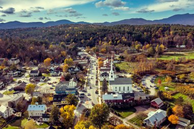Stowe, Vermont 'taki ana cadde ve beyaz topluluk kilisesinin hava manzarası. Düşen çok renkli ağaçları olan dağlar