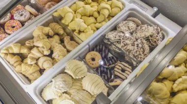 Dondurulmuş çörekler ve briçler büyük bir marketteki market buzdolabında ya da pastanedeki süpermarkette. Donmuş bir gıda dükkanında dondurulmuş briç ve çörekler.