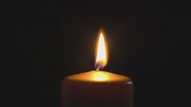 Büyük sarı mum ışıkları ve söndürme, siyah bir arka planda izole edilmiş. Yavaş çekim, merkezi çerçeve kapat.