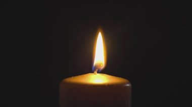 Büyük sarı mum ışıkları ve söndürme, siyah bir arka planda izole edilmiş. Yavaş çekim, merkezi çerçeve kapat.