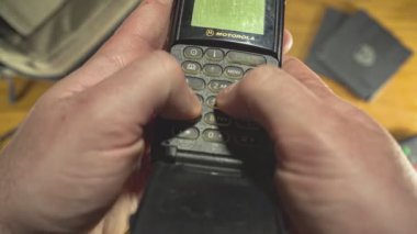 MILAN, İTALYA 21 EKİM 2021: 80 'lerden kalma eski bir cep telefonu kullanıyor. 80 'lerin retro masasının üstünden en üst görünüm.